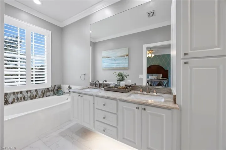 Primary bathroom with new floor tile, plantation shutters and granite countertops