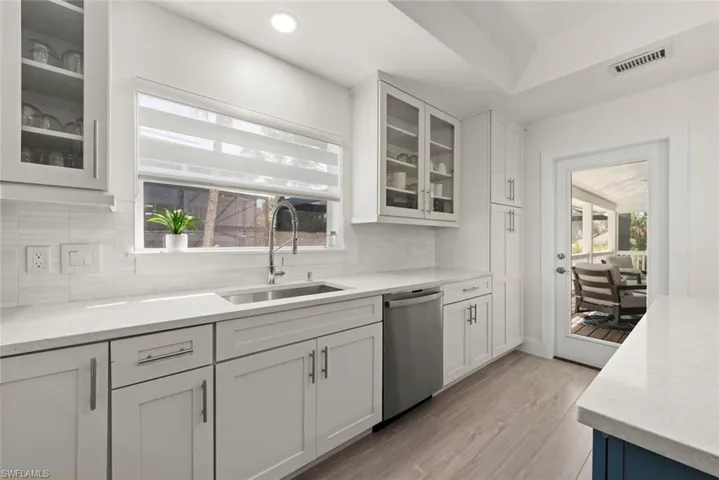 Kitchen featuring glass fronted cabinets, white cabinetry, light stone countertops, light wood-type flooring, and recessed lighting