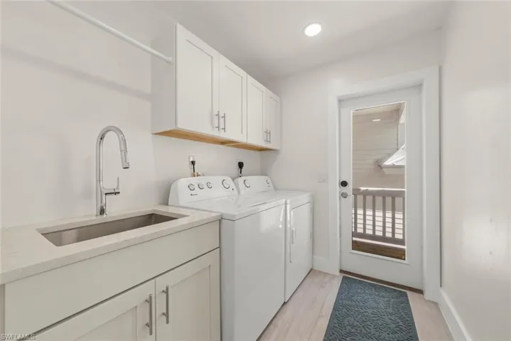 Laundry room with light wood-style flooring, cabinet space, and washer and clothes dryer