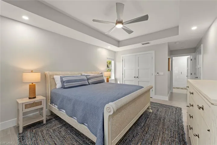 Bedroom featuring recessed lighting, a raised ceiling, a closet, ceiling fan, and light wood-style flooring