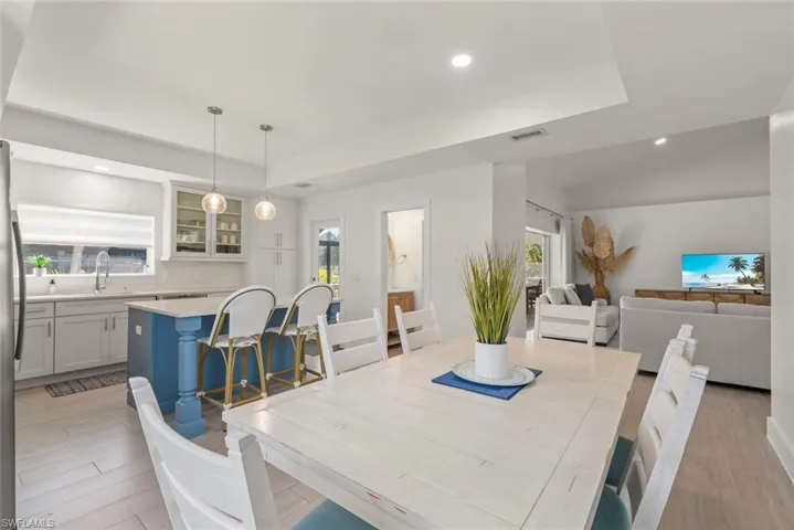 Dining room featuring recessed lighting, light wood-type flooring, plenty of natural light, and a tray ceiling