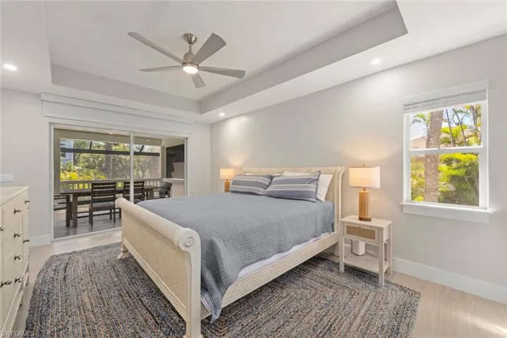 Bedroom with multiple windows, a tray ceiling, recessed lighting, a ceiling fan, and access to outside