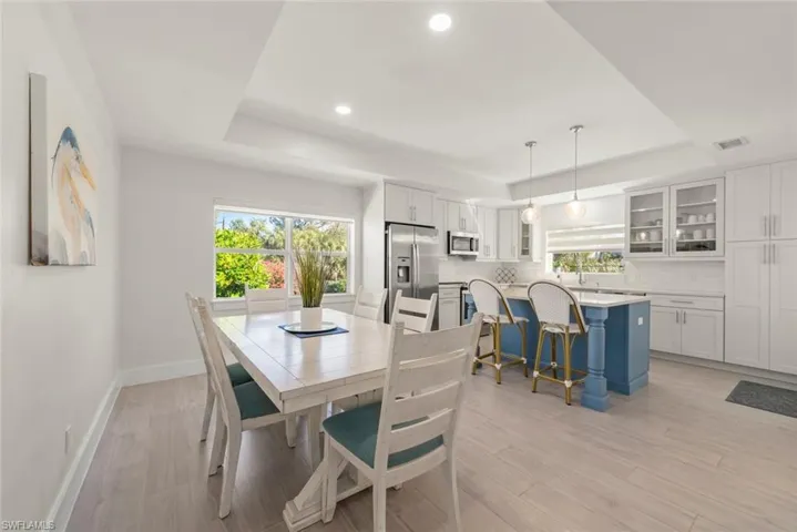 Dining area featuring a tray ceiling, healthy amount of natural light, recessed lighting, and light wood-style floors
