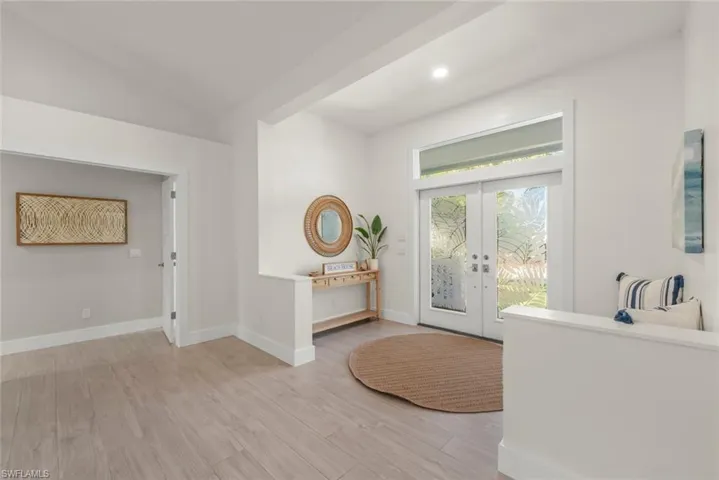 Entrance foyer featuring french doors, light wood finished floors, lofted ceiling, and recessed lighting