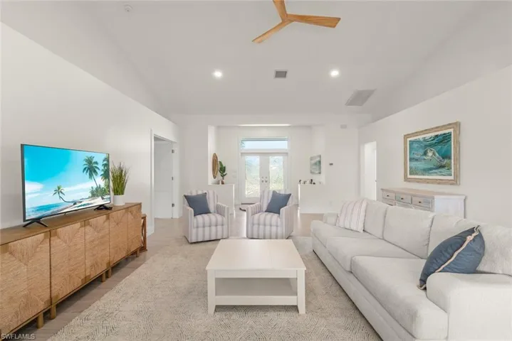 Living room with vaulted ceiling, ceiling fan, light wood-style flooring, french doors, and recessed lighting