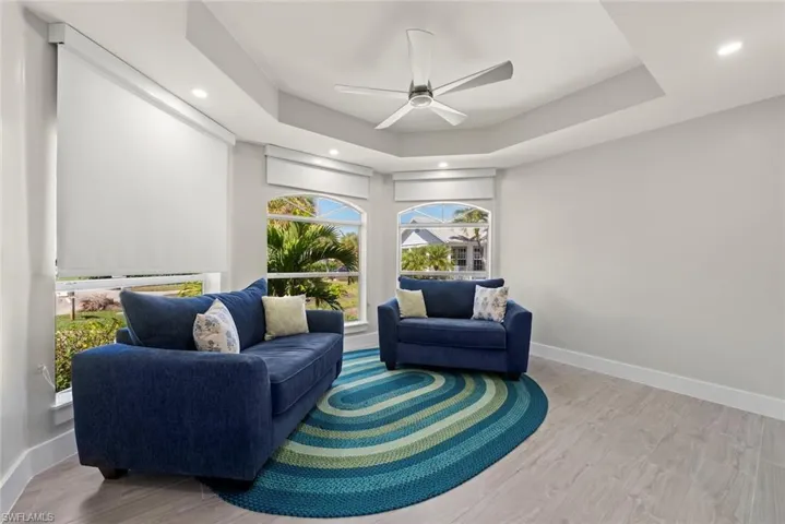 Living area featuring ceiling fan, light wood-style flooring, recessed lighting, and a tray ceiling