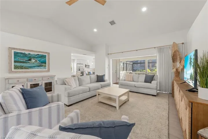 Living room with a ceiling fan, lofted ceiling, recessed lighting, and light wood-style flooring