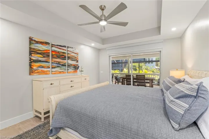 Bedroom featuring recessed lighting, access to exterior, ceiling fan, wood finished floors, and a tray ceiling