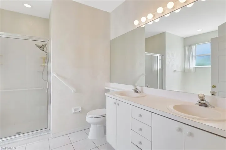 Bathroom featuring a stall shower, tile patterned floors, double vanity, and a sink