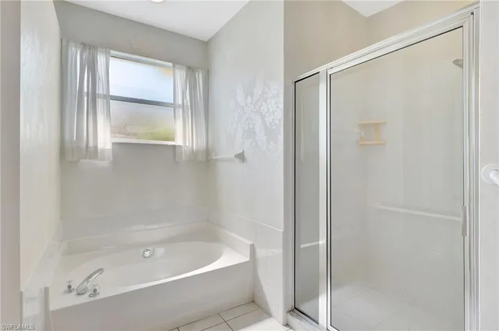 Full bathroom featuring tile patterned floors, a garden tub, and a shower stall