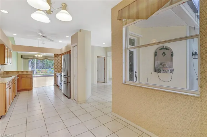 Kitchen with light countertops, a sink, freestanding refrigerator, light tile patterned floors, and ceiling fan with notable chandelier