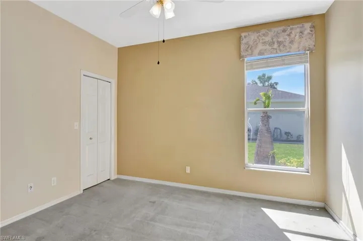 Carpeted spare room featuring baseboards and a ceiling fan