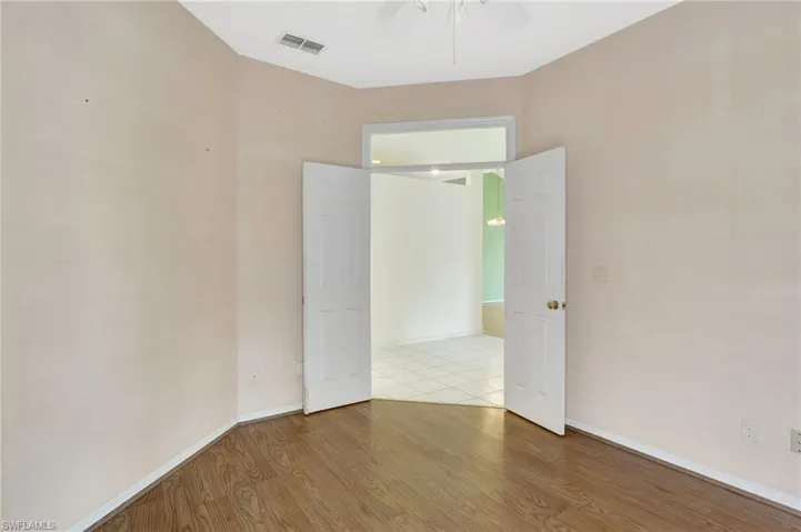 Spare room featuring baseboards, visible vents, a ceiling fan, and wood finished floors