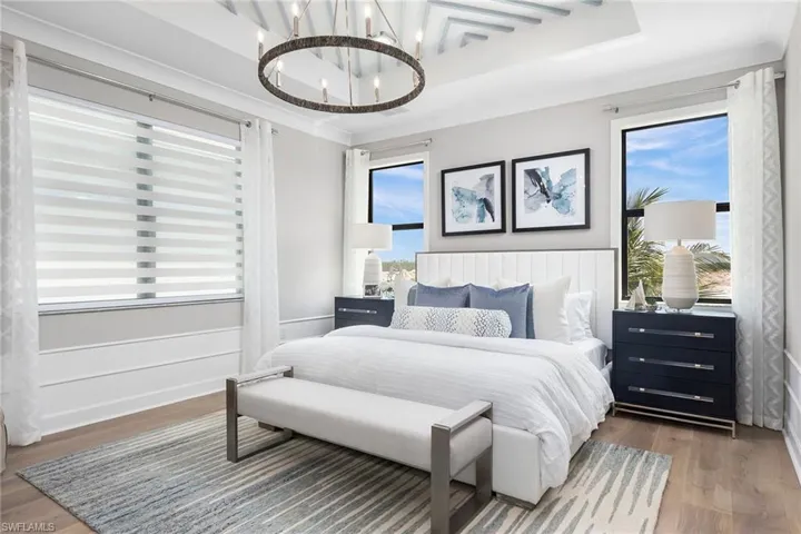 Bedroom with hardwood / wood-style flooring, a chandelier, a raised ceiling, and multiple windows