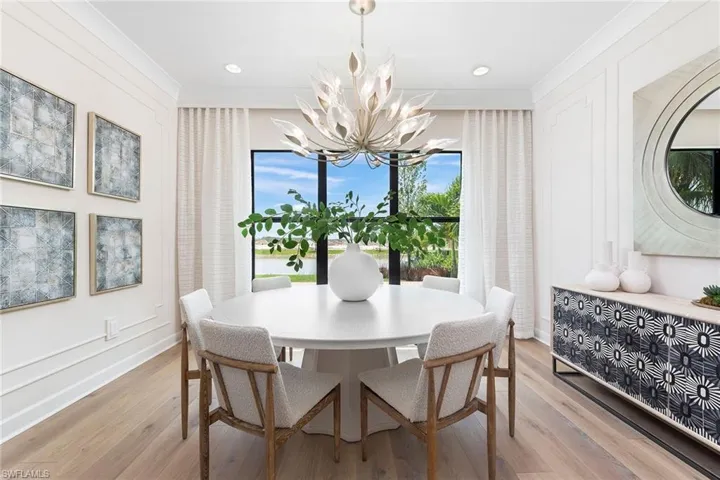 Dining room with light hardwood / wood-style floors, crown molding, and an inviting chandelier