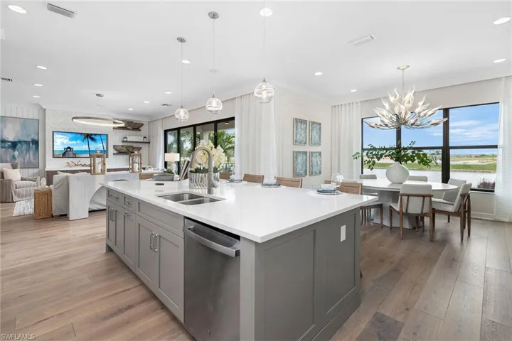 Kitchen featuring stainless steel dishwasher, gray cabinetry, sink, and a center island with sink