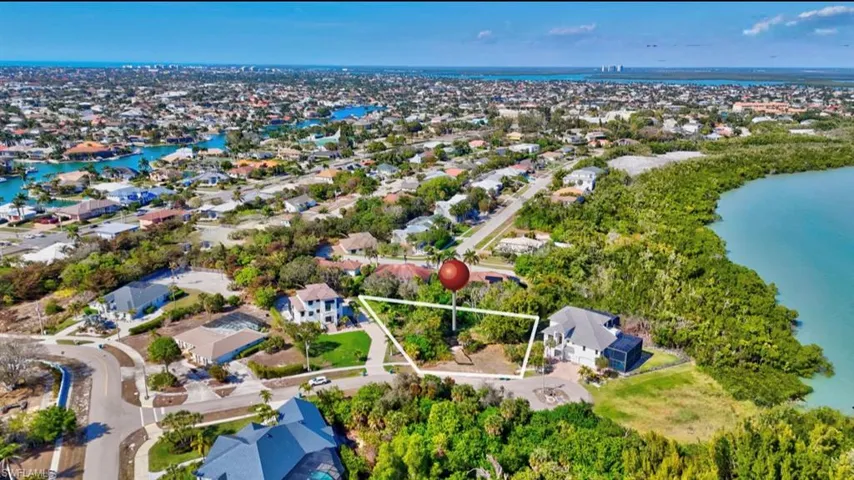 Aerial perspective of suburban area featuring a large body of water and property parcel outlined