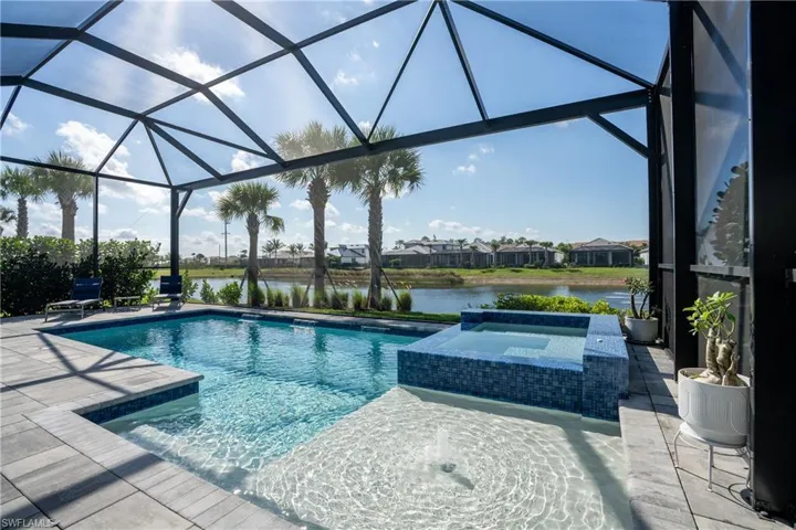 Relaxing pool / spa featuring glass enclosure, a water view, a residential view, and a sunroom