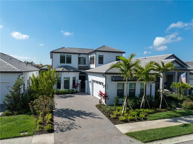 Traditional-style home featuring decorative driveway, an attached garage, stucco siding, and a tiled roof