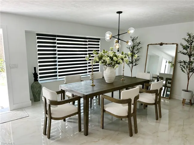 Dining space featuring a chandelier, a textured ceiling, and light marble finish floors