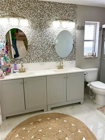 Bathroom featuring double vanity, tasteful backsplash, a shower with door, and tile walls
