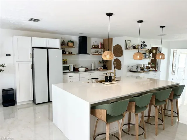 Kitchen featuring open shelves, white appliances, white cabinets, pendant lighting, and ventilation hood