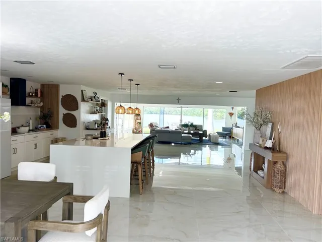 Dining space featuring healthy amount of natural light, light marble finish floors, and wood walls