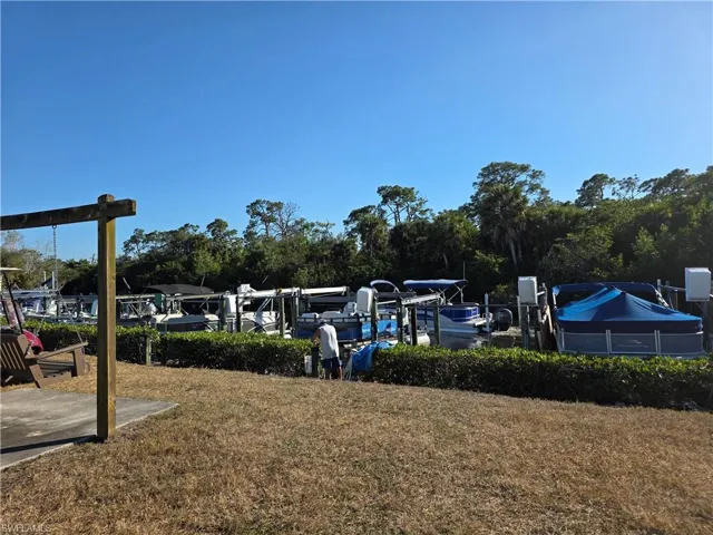 View of grassy yard with view of wooded area and a dock