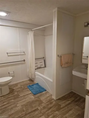 Bathroom featuring a textured ceiling and shower / bath combo with shower curtain