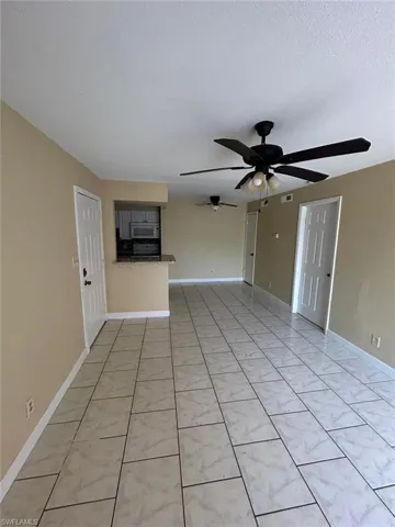 Unfurnished living room with light tile patterned floors, ceiling fan, and a textured ceiling