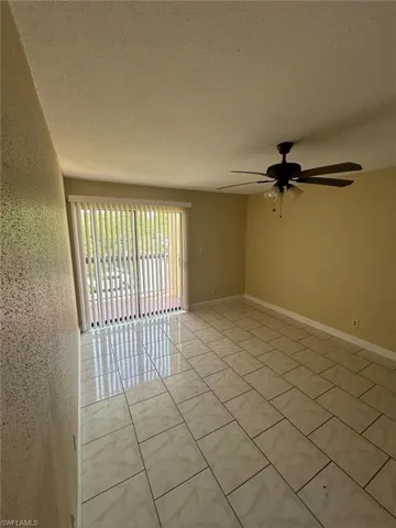 Unfurnished room featuring a textured ceiling, light tile patterned floors, and a ceiling fan