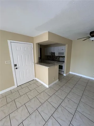 Kitchen with white appliances, a peninsula, a ceiling fan, open floor plan, and a textured ceiling