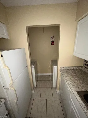 Laundry area with light tile patterned flooring and washer / dryer
