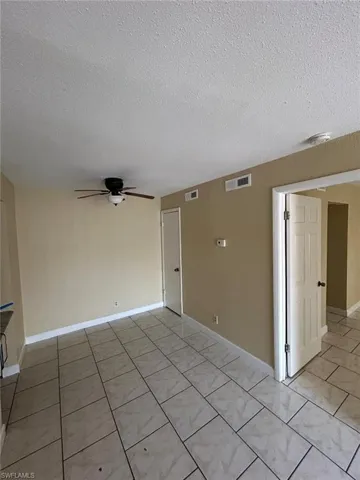 Unfurnished room with a textured ceiling, light tile patterned flooring, and a ceiling fan