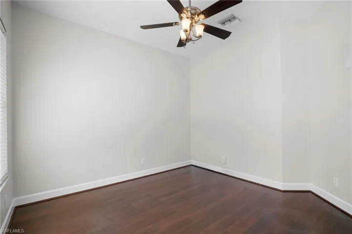 Unfurnished room with dark wood-type flooring and a ceiling fan