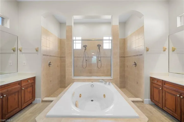 Full bath with vanity, a walk in shower, and a jetted tub