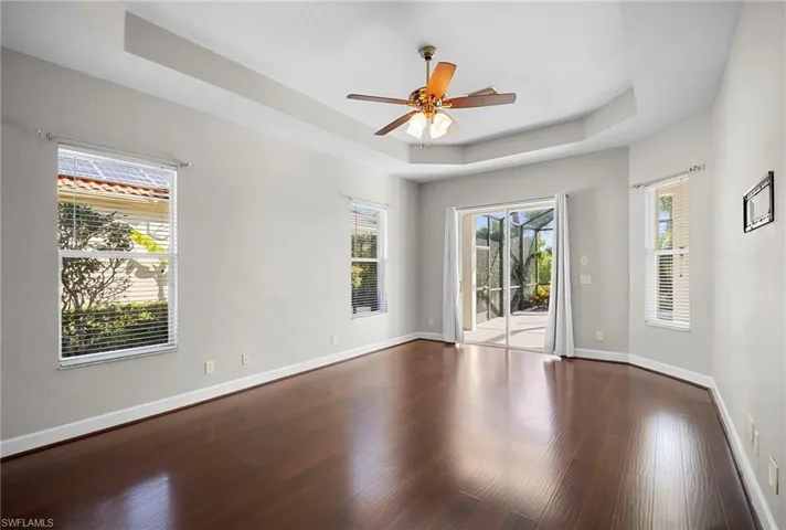 Unfurnished room with a raised ceiling, wood finished floors, and a ceiling fan