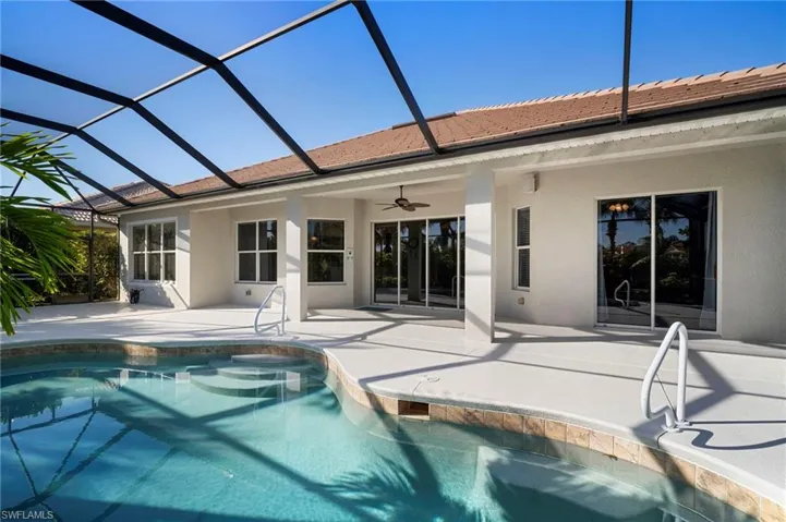 Outdoor pool with glass enclosure, a patio, and a sunroom