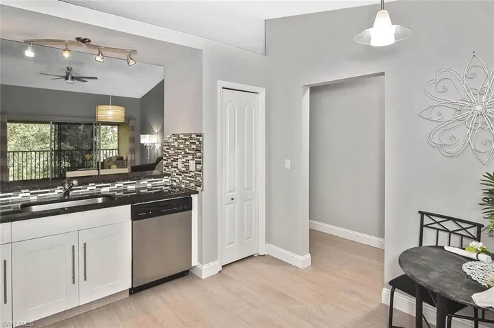 Kitchen featuring stainless steel dishwasher, dark countertops, decorative backsplash, white cabinets, and ceiling fan
