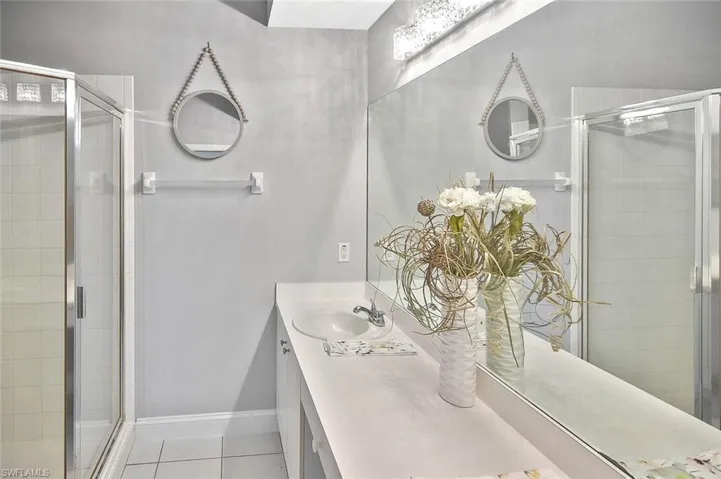 Bathroom with a stall shower, tile patterned floors, and vanity