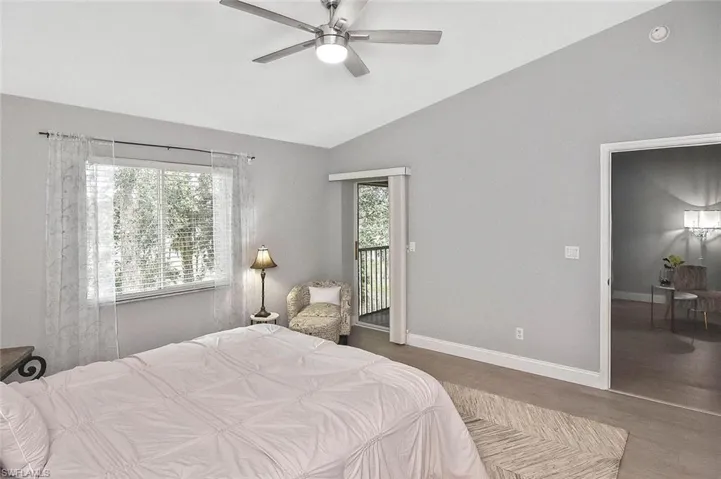 Bedroom featuring access to exterior, wood finished floors, lofted ceiling, and ceiling fan