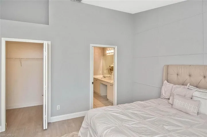 Bedroom with a spacious closet, wood finished floors, a closet, and ensuite bath