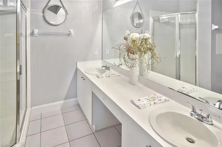 Full bath featuring double vanity, a shower stall, and tile patterned floors