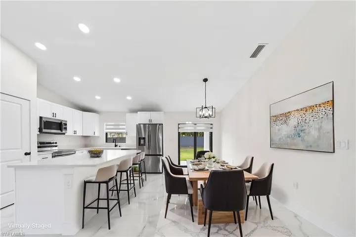 Open-concept kitchen and dining area featuring a vaulted ceiling and recessed lighting