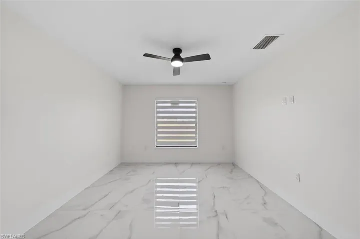 Spacious room featuring large format tile flooring, a window with horizontal blinds, a ceiling fan with integrated lighting, and neutral wall finishes