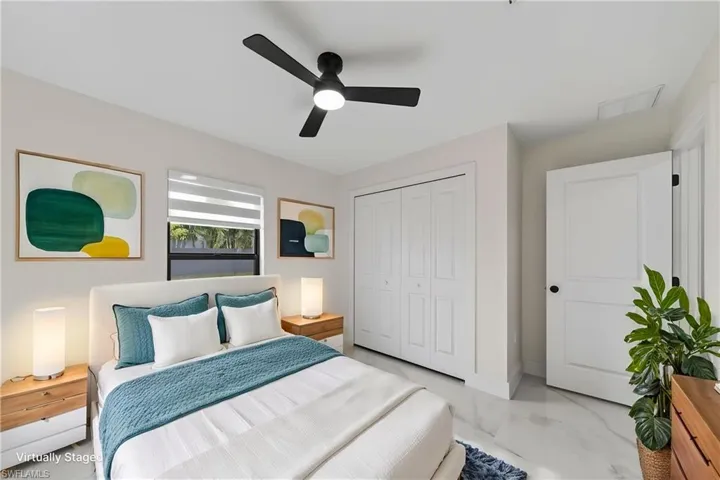 Spacious room featuring large windows with horizontal blinds, a modern ceiling fan, and white bifold closet doors