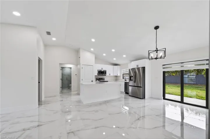 Open-concept living space featuring high vaulted ceilings and polished marble-look flooring