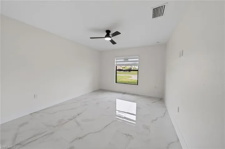 Spacious room featuring large format tile flooring, a window with horizontal blinds, a ceiling-mounted fan with integrated lighting, and flush-mounted ceiling vents
