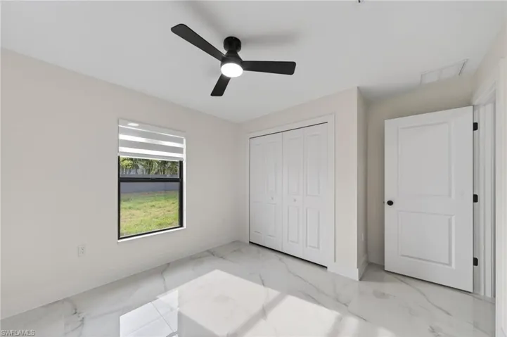 Bright room with large format tile flooring, a window featuring horizontal blinds, and a contemporary ceiling fan with integrated lighting