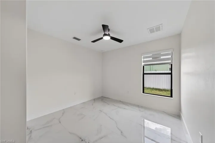 Spacious room featuring large format porcelain tile flooring, a contemporary ceiling fan with integrated lighting, a single window with blinds, and white painted walls